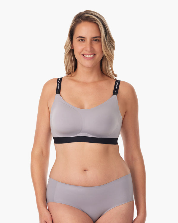 Woman modeling grey Momcozy nursing bra, featuring adjustable straps for comfort.