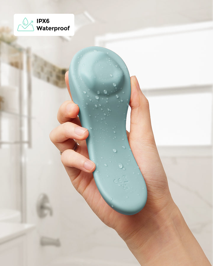 Hand holding blue waterproof lactation massager with IPX6 certification in a bathroom setting